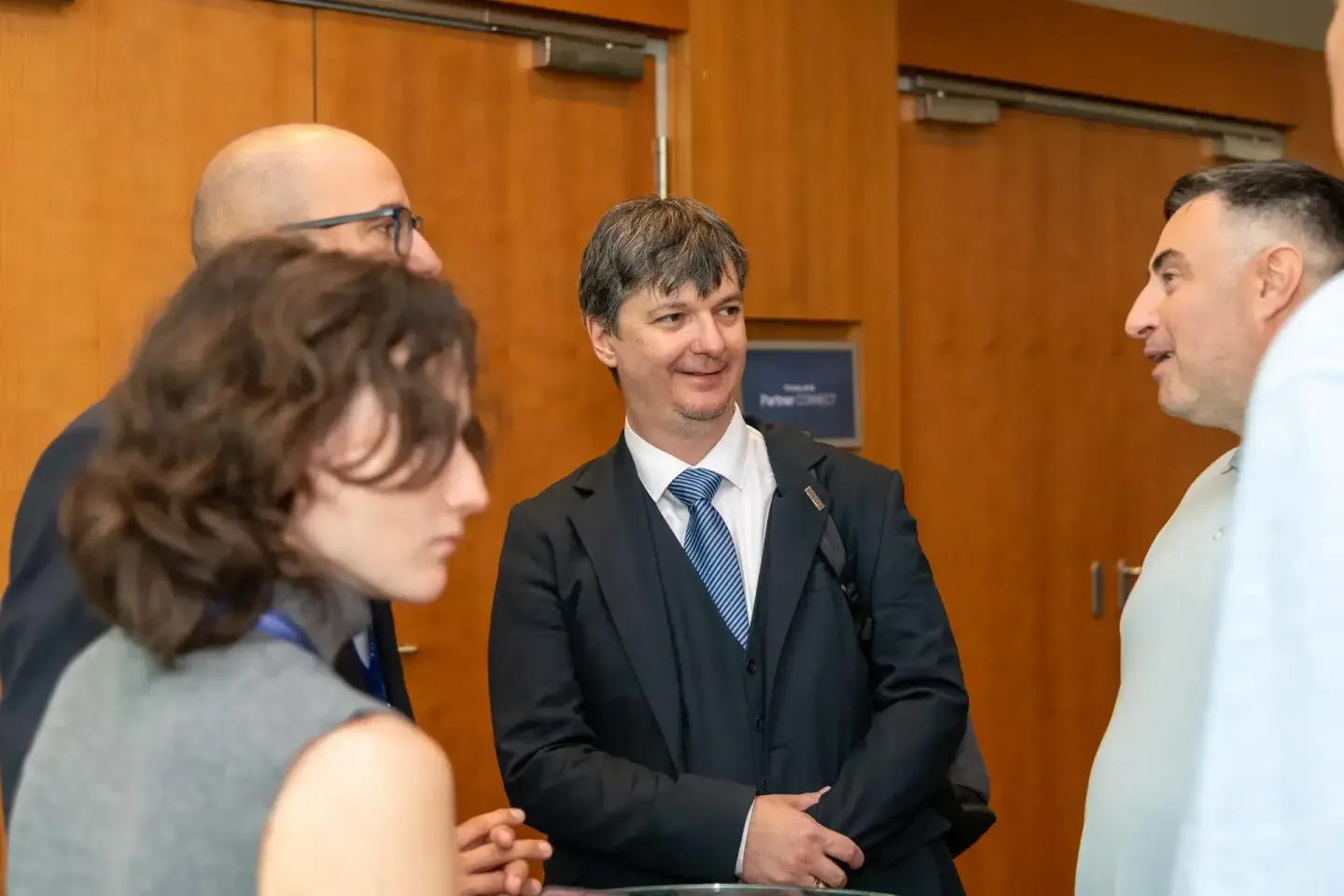 Vier Personen im Gespräch bei einem Firmenevent Wien, professionelle Networking-Situation in modernem Veranstaltungsraum