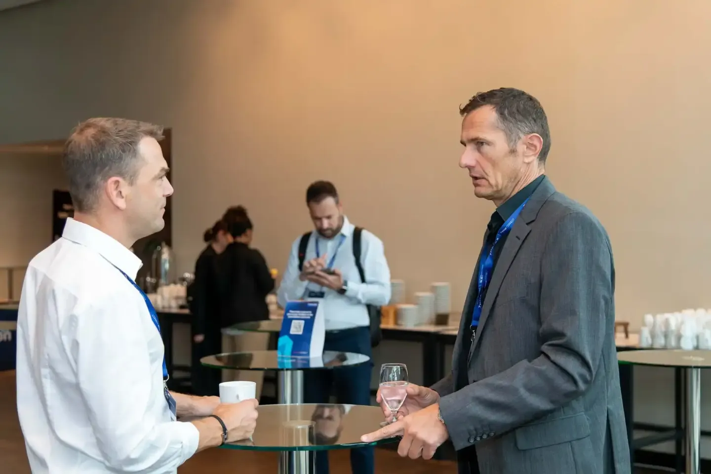 Zwei Geschäftsmänner führen ein Gespräch auf einem Firmenevent in Wien, beide tragen Ausweishalter