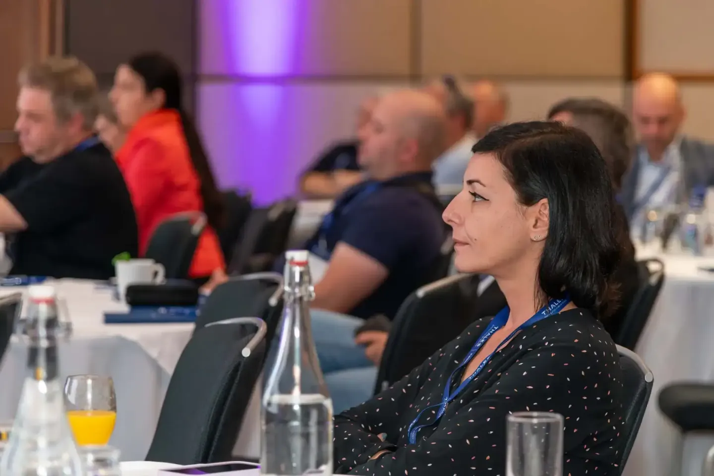 Teilnehmerin mit Namensschildern bei Thales-Firmen­event in Wien, im Hintergrund weitere Gäste an Konferenz­tisch