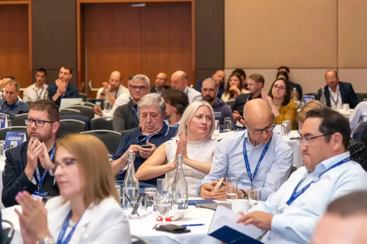 Teilnehmer einer Geschäftskonferenz sitzen an Tischen während einer Präsentation, Eventfotografie Wien dokumentiert die Firme