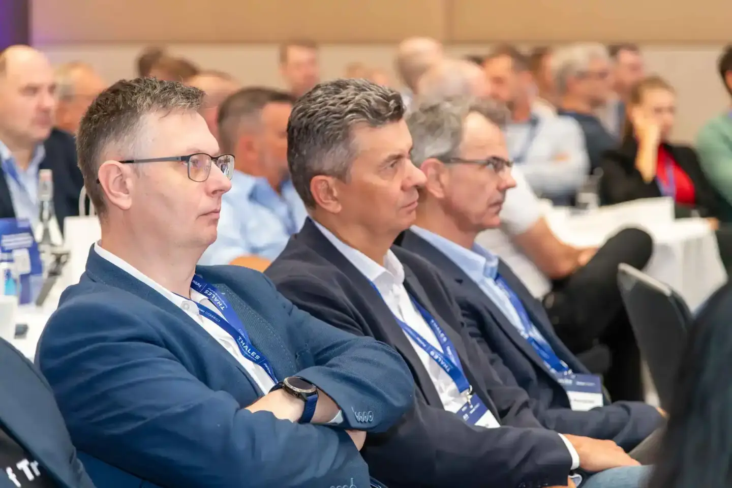 Teilnehmer in Business-Kleidung mit Namensschildern sitzen aufmerksam bei einer Thales-Konferenz – Eventfotograf Wien dokumen