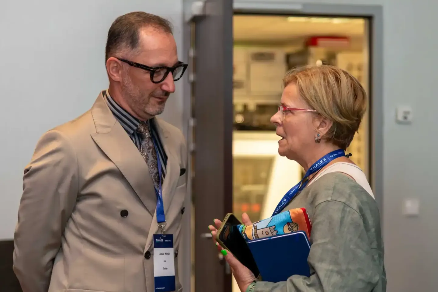 Zwei Personen im Gespräch bei einem Firmenevent Wien - Mann in Beige-Blazer mit Brille und Frau mit Namensschildern und blaue