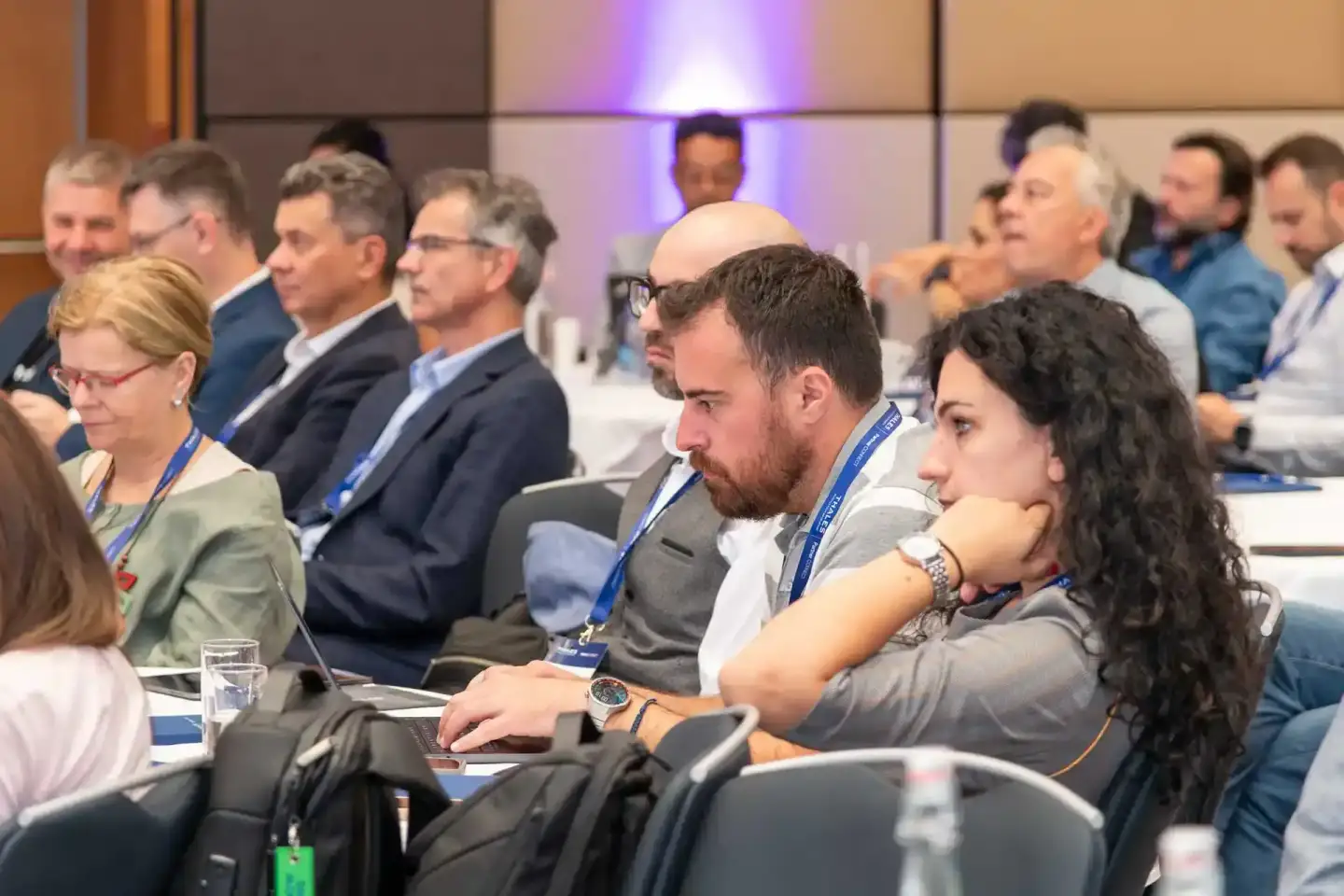 Teilnehmer eines Firmenevent Wien sitzen in einem Konferenzraum und verfolgen aufmerksam eine Präsentation, viele tragen blau