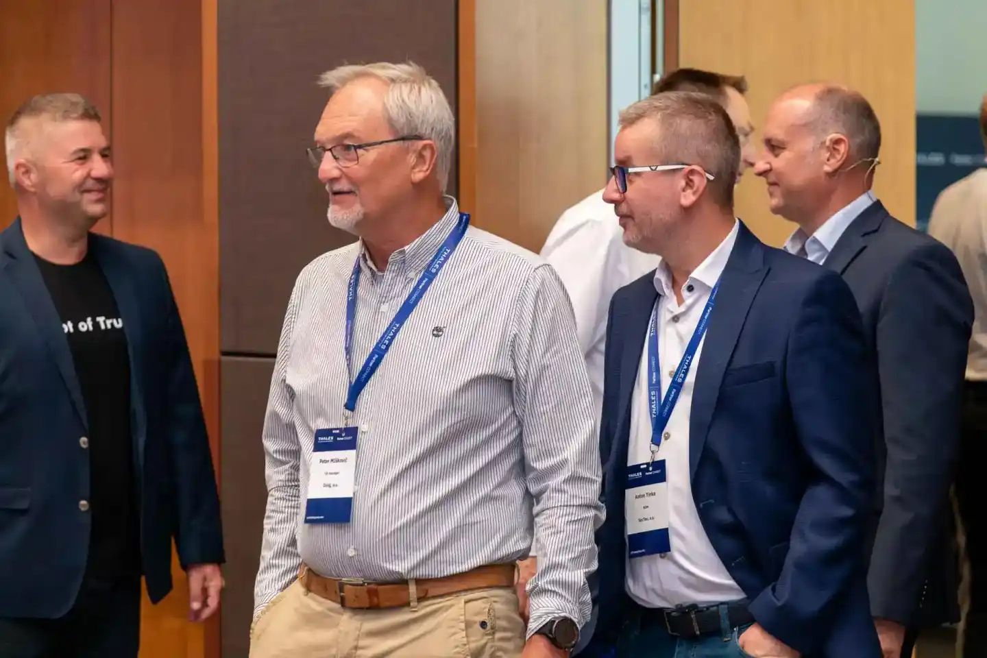 Vier Geschäftsmänner im Gespräch bei einem Firmenevent Wien, zwei tragen Namensschilder und Lanyards