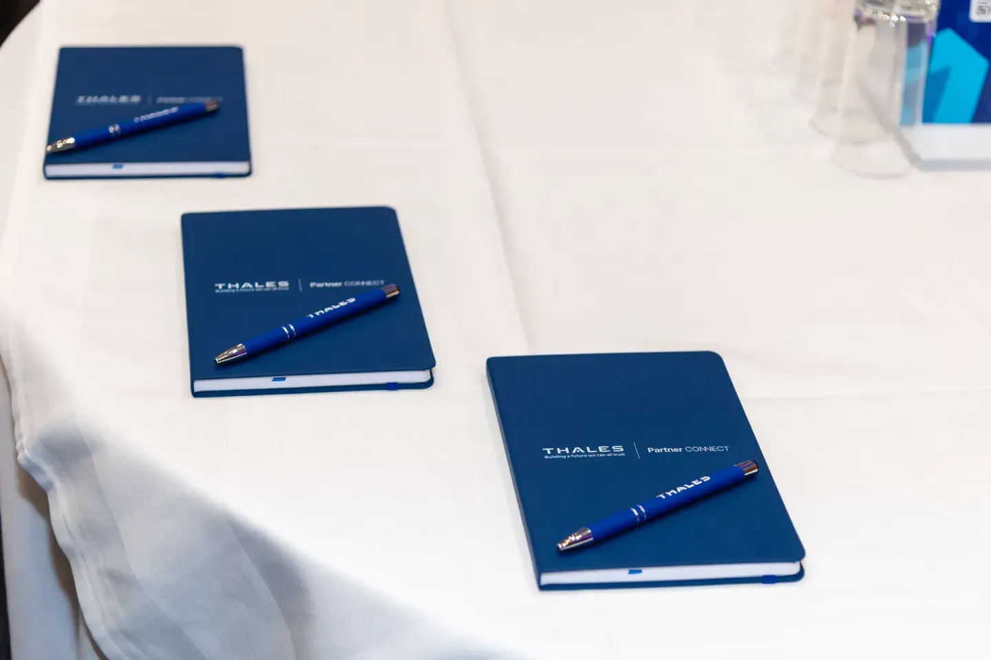 Thales Partner Connect Event: Blaue Notizbücher und Kugelschreiber auf weißem Tisch bei Firmenevent in Wien