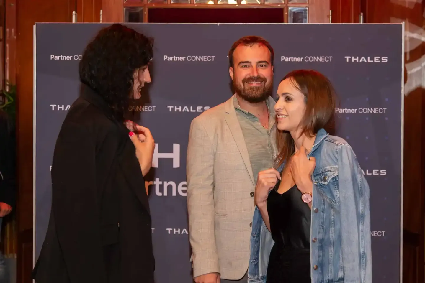 Drei Personen im Gespräch vor Thales und Partner Connect Backdrop bei Firmenevent Wien