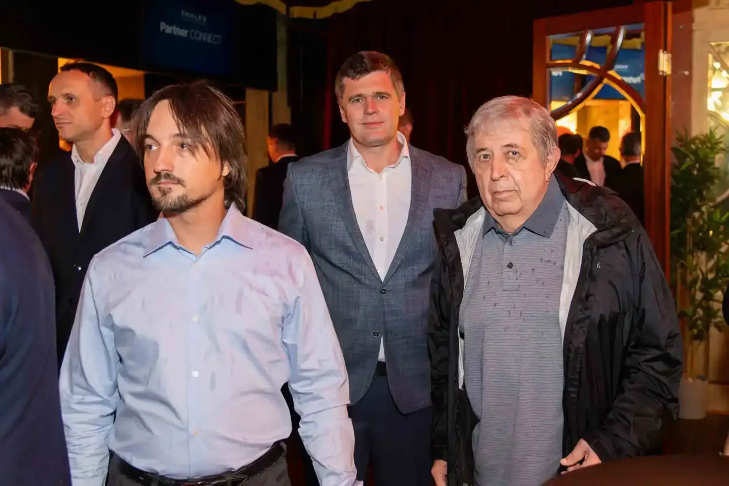 Vier Geschäftsmänner auf einem Firmenevent in Wien, drei stehen zusammen und schauen nach vorne