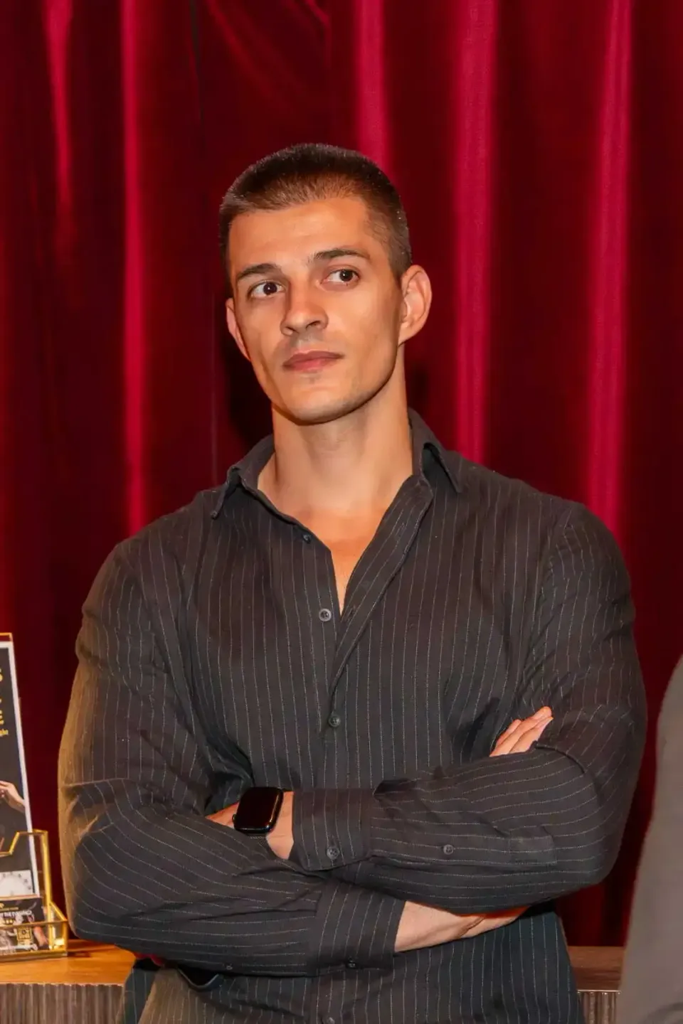 Professioneller Mann in schwarzem Nadelstreifenhemd vor rotem Vorhang bei Firmenevent Wien