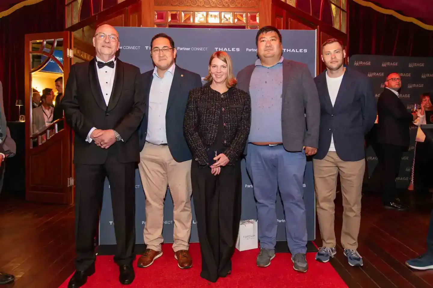 Fünf Personen posieren auf rotem Teppich vor Thales-Bannern bei Firmenevent Wien