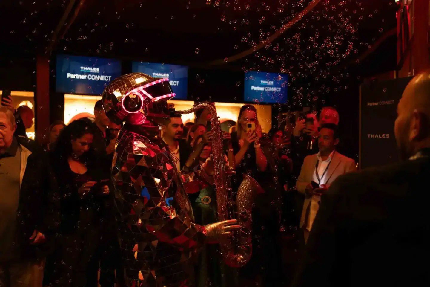 Performer in rotem futuristischen Kostüm mit leuchtender Kopfbedeckung spielt Saxophon auf Thales Partner Connect Eventfotogr