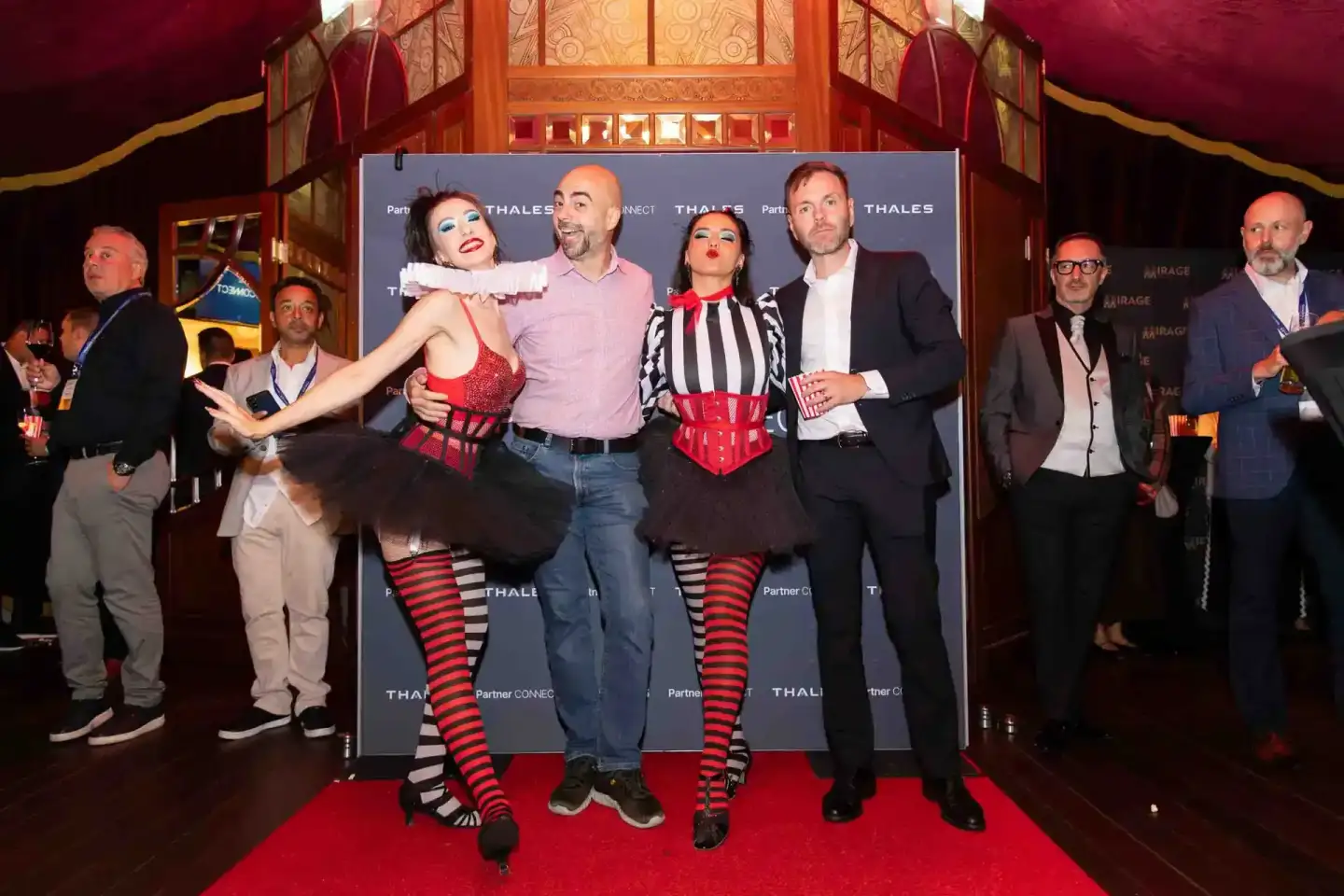 Eventfotograf Wien dokumentiert Thales Firmenevent mit zwei Performerinnen in roter Bühnenkleidung und männlichen Gästen auf 