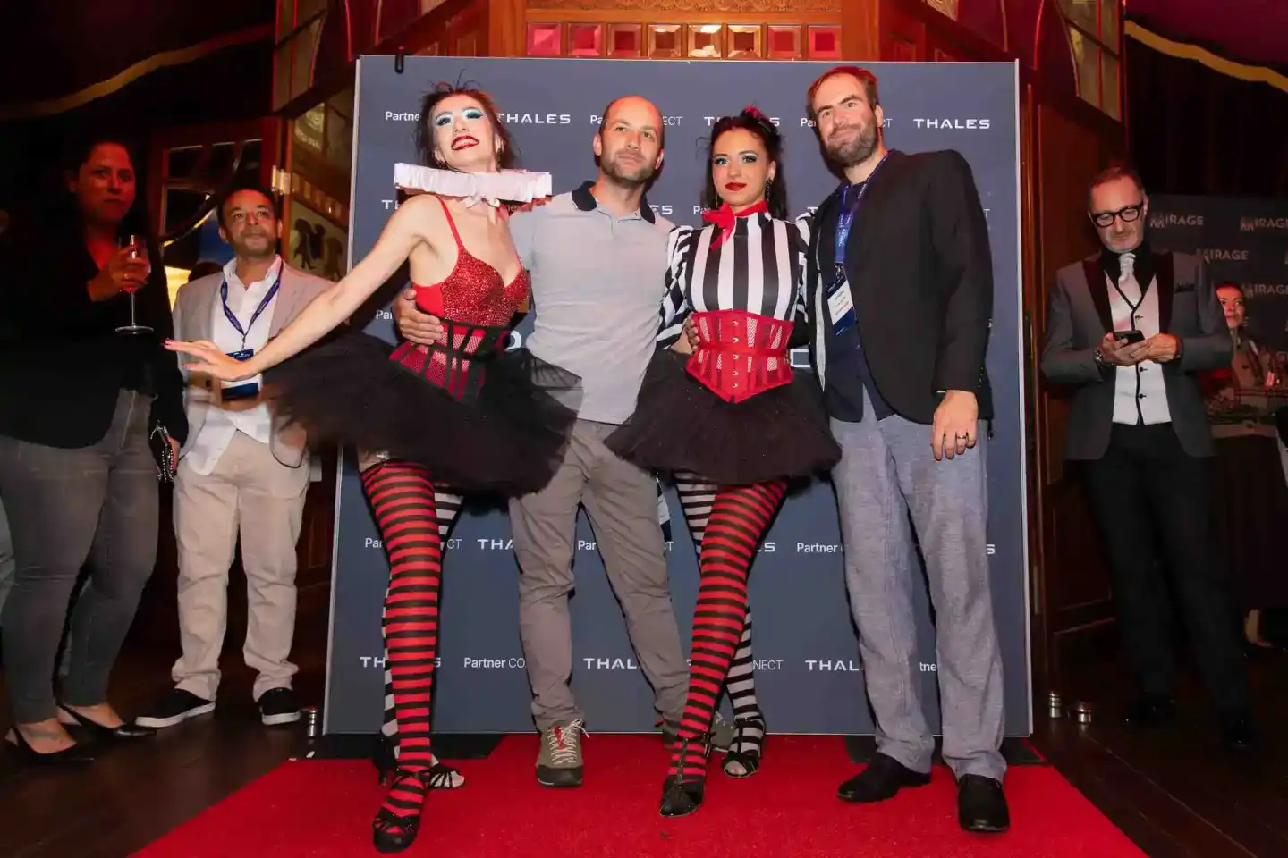 Eventfotograf Wien dokumentiert Thales Firmenevent mit Künstlern in roten Kostümen auf rotem Teppich vor Backdrop
