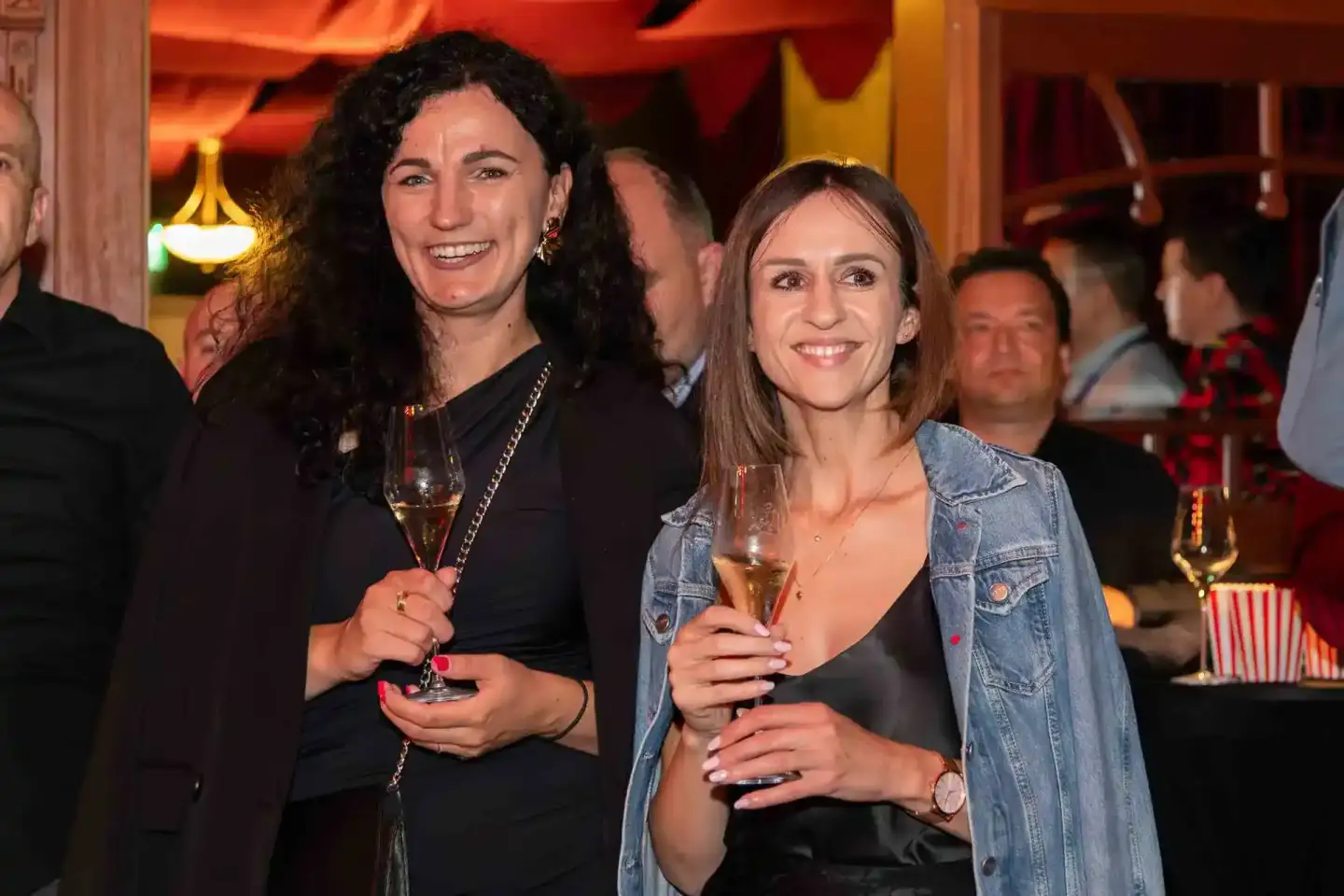 Zwei Frauen mit Sektgläsern auf einem Firmenevent in Wien, lächelnd in eleganter Atmosphäre
