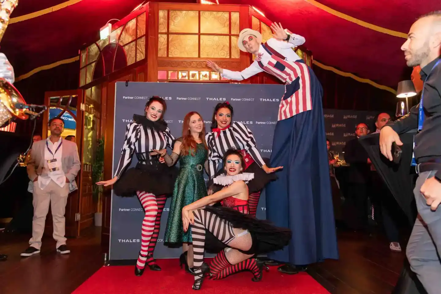 Eventfotograf Wien dokumentiert Thales Firmenevent mit Künstlern in Zirkuskostümen vor rotem Hintergrund