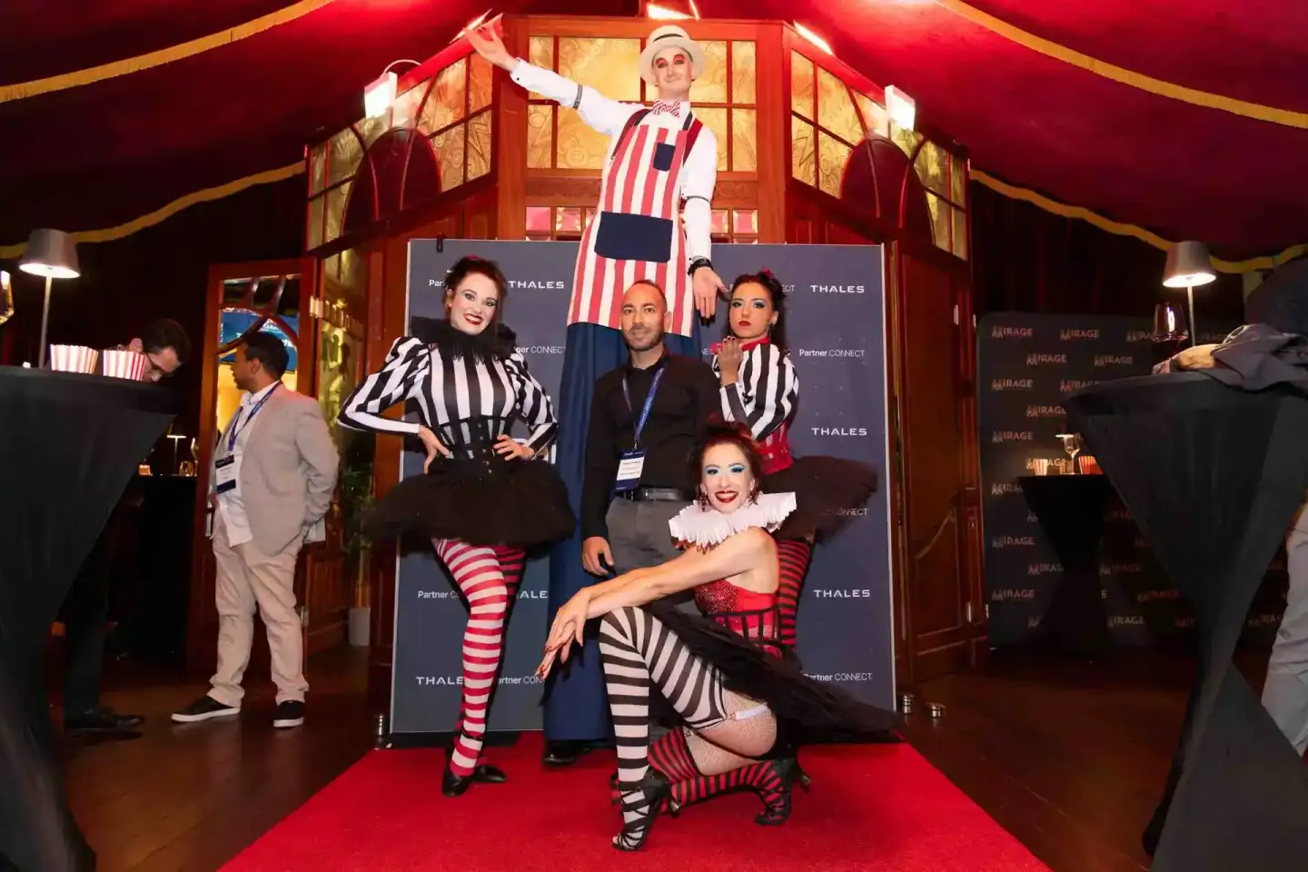 Eventfotograf Wien dokumentiert Zirkus-Themed Firmenevent mit Künstlern in rot-weißen Kostümen und Performer auf Podium