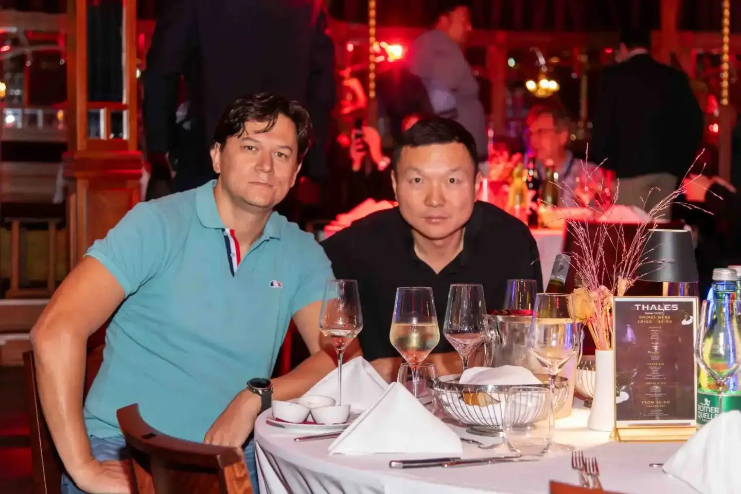 Zwei Gäste beim Thales Firmenevent in Wien sitzen am elegant gedeckten Tisch mit Weingläsern und genießen die festliche Atmos