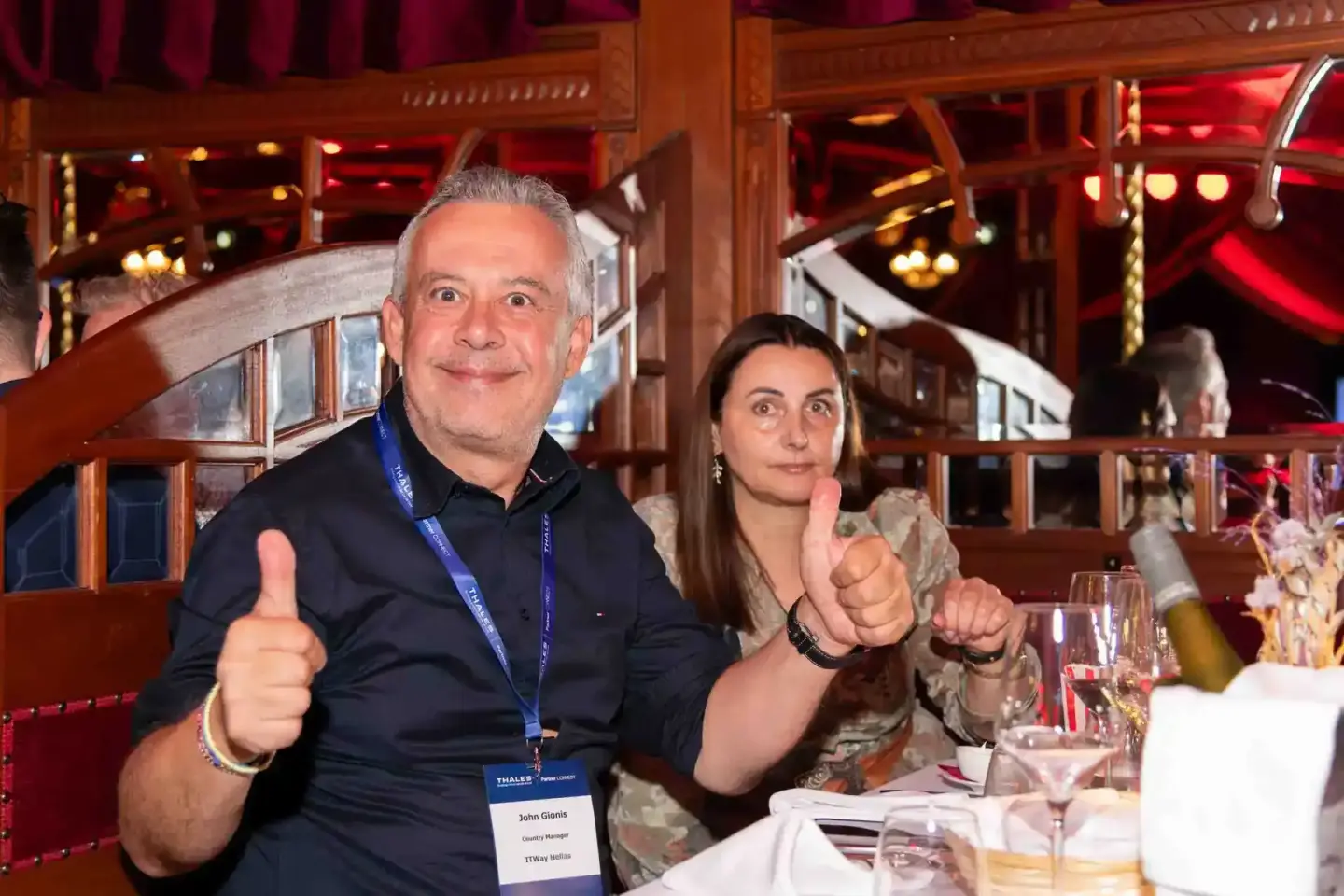 Zwei Personen geben Daumen-hoch-Gesten bei einem Firmenevent Wien in eleganter Veranstaltungslocation mit roter Beleuchtung