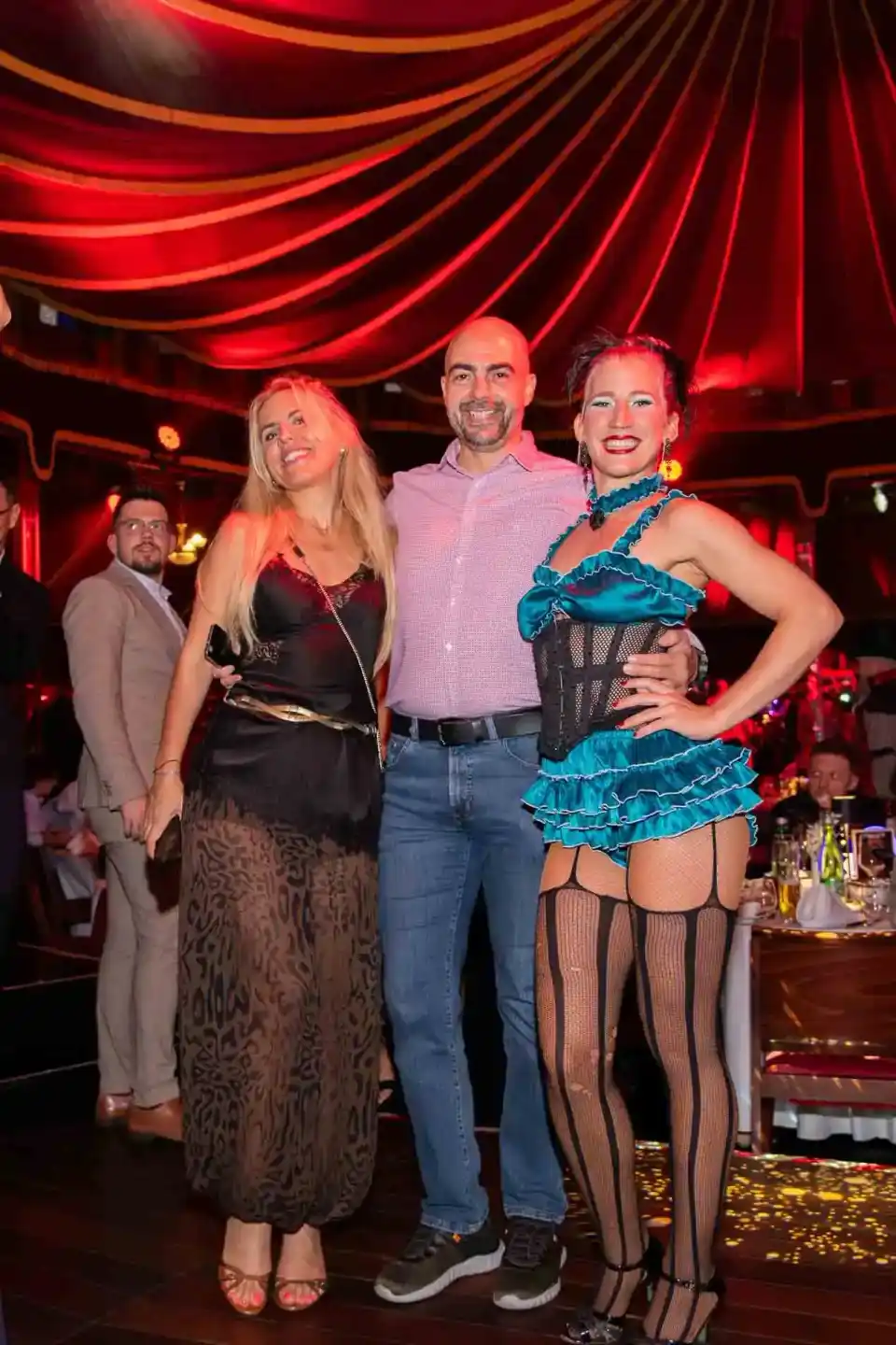 Drei Personen posieren lächelnd vor roter Bühnenbeleuchtung auf einem Firmenevent Wien