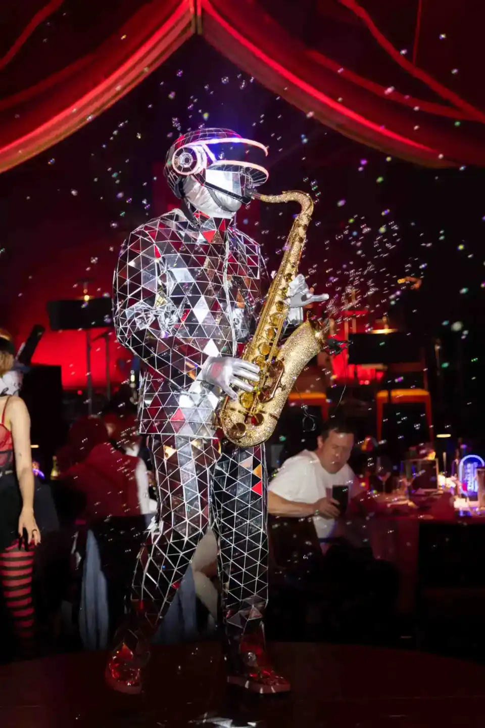 Leuchtende Roboterfigur mit Saxophon auf Firmenevent Wien, umgeben von bunten Lichtern und Publikum