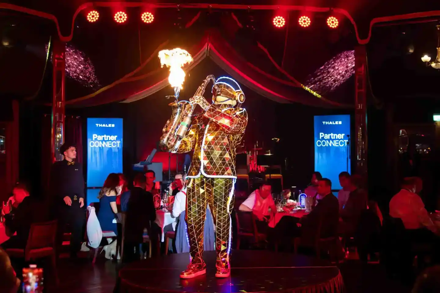 Spektakuläre Eventfotografie Wien: Leuchtende Astronauten-Figur mit Feuereffekt auf Bühne beim Thales Partner Connect Event