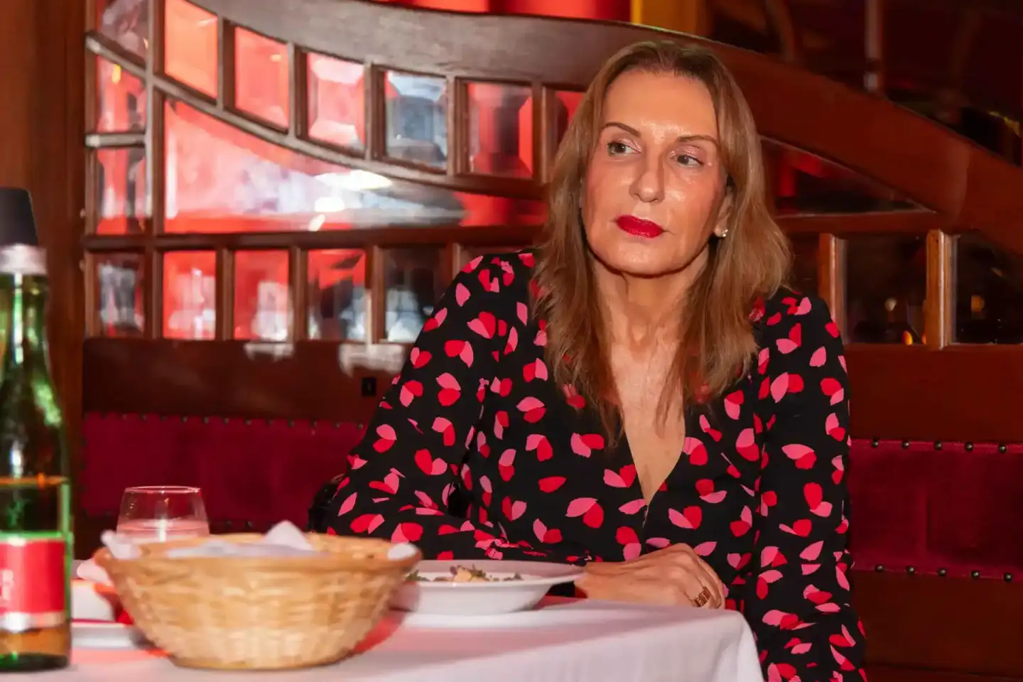 Elegante Frau in rotem Leoparden-Muster Blazer sitzt beim Firmenevent Wien an gedecktem Tisch in Restaurant mit roten Neon-Fe