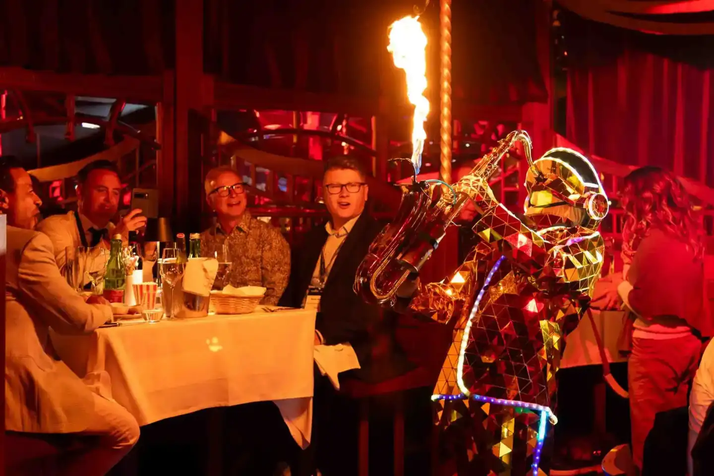 Eventfotograf dokumentiert Gäste an Tisch während Thales Firmevent in Wien mit Saxophonspieler und Flammeneffekt