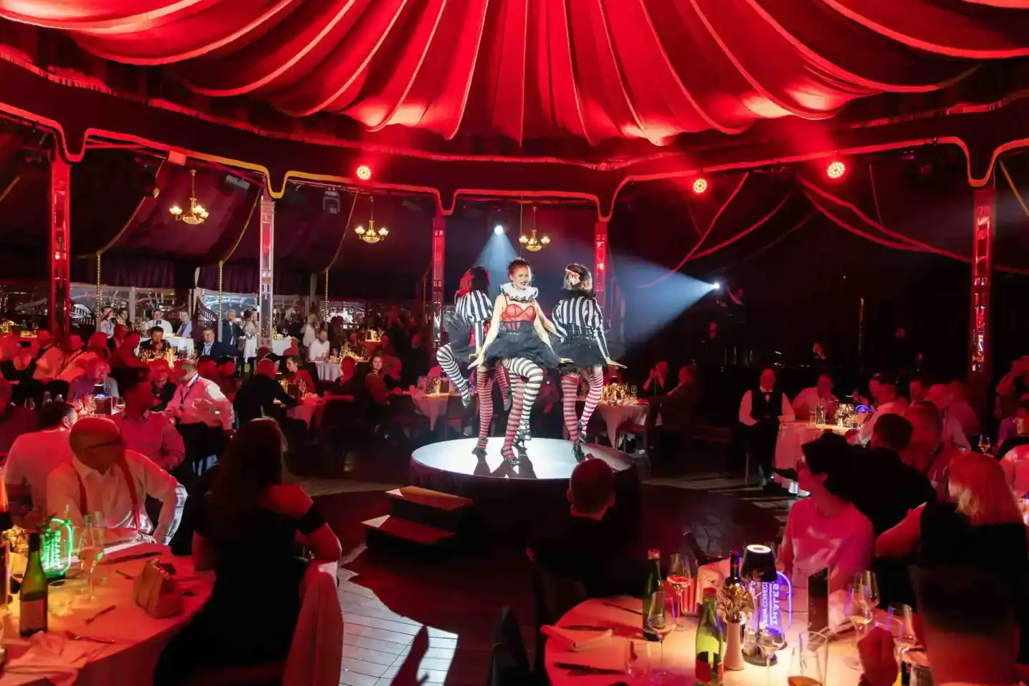 Zirkusperformerin auf beleuchteter Bühne während Firmenevent Wien im roten Zirkuszelt mit Publikum