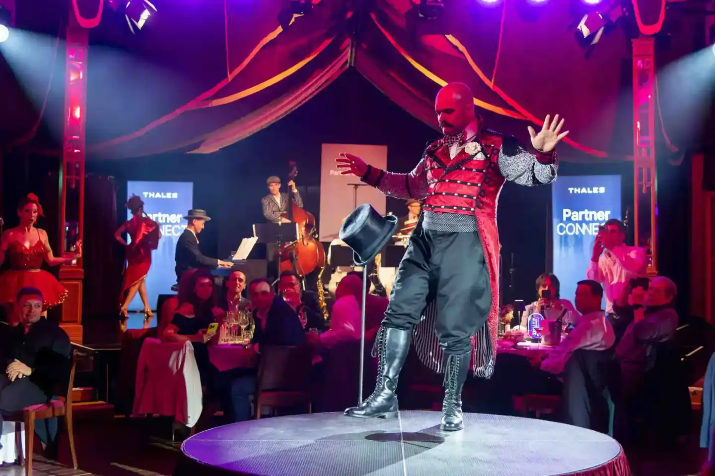 Performer in rotem Paillettenanzug auf der Bühne während eines Thales Firmenévents in Wien, umgeben von Gästen und Live-Musik
