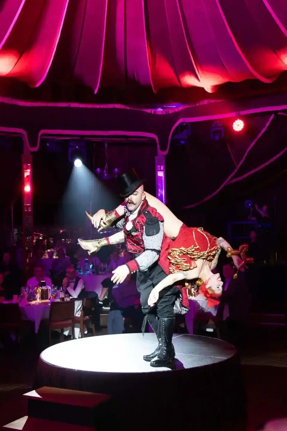 Akrobat in rotem Kostüm führt spektakuläre Luftakrobatik auf Bühne auf – Eventfotografie Wien