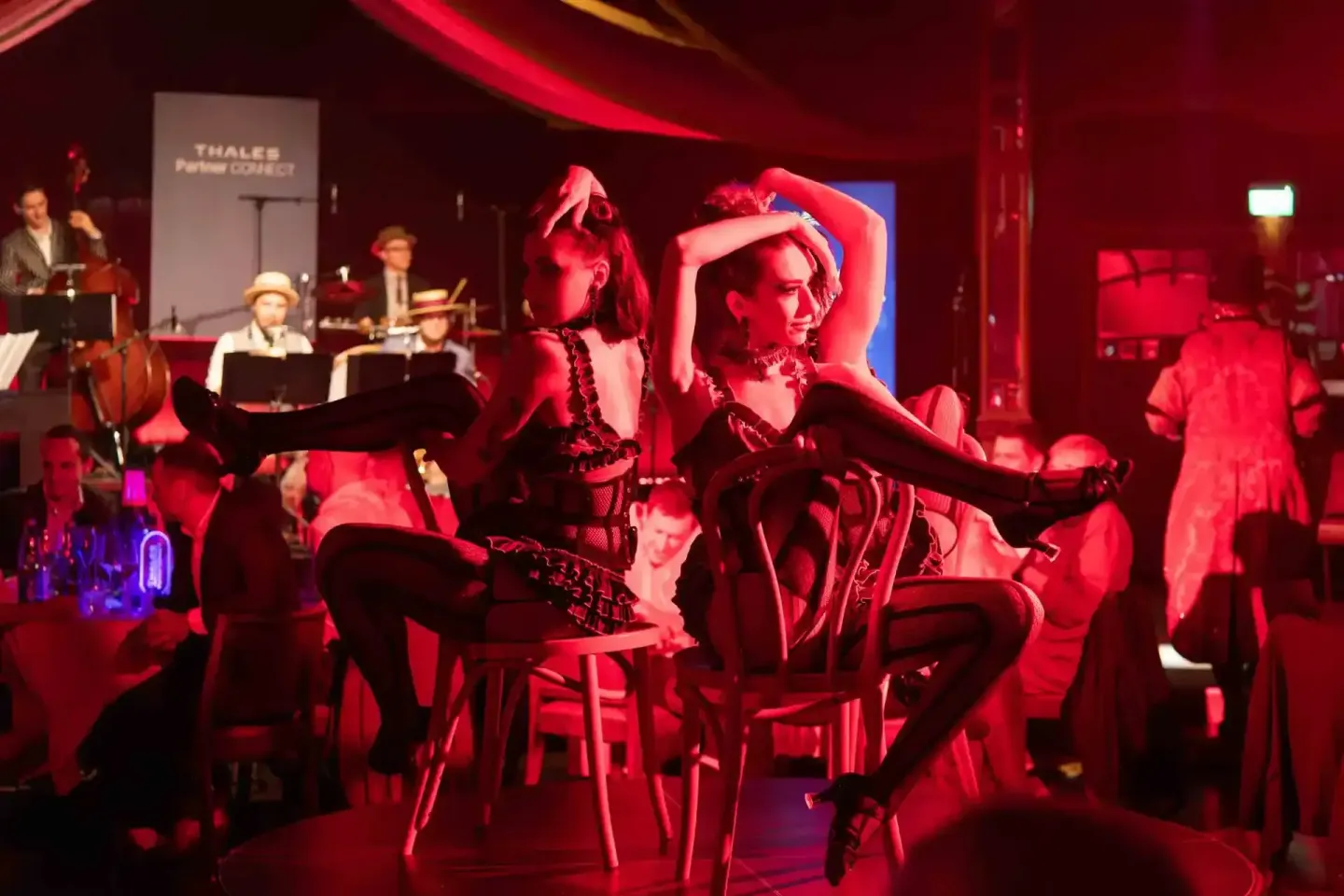 Zwei Performerinnen in schwarzer Bühnenkleidung tanzen bei einem Thales Firmenevent Wien unter roter Beleuchtung auf der Bühn