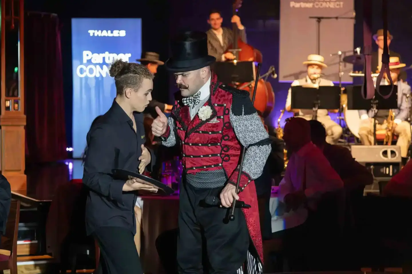 Eventfotograf dokumentiert Moderator in rotem Smoking bei Thales Partner Connect Veranstaltung auf der Bühne