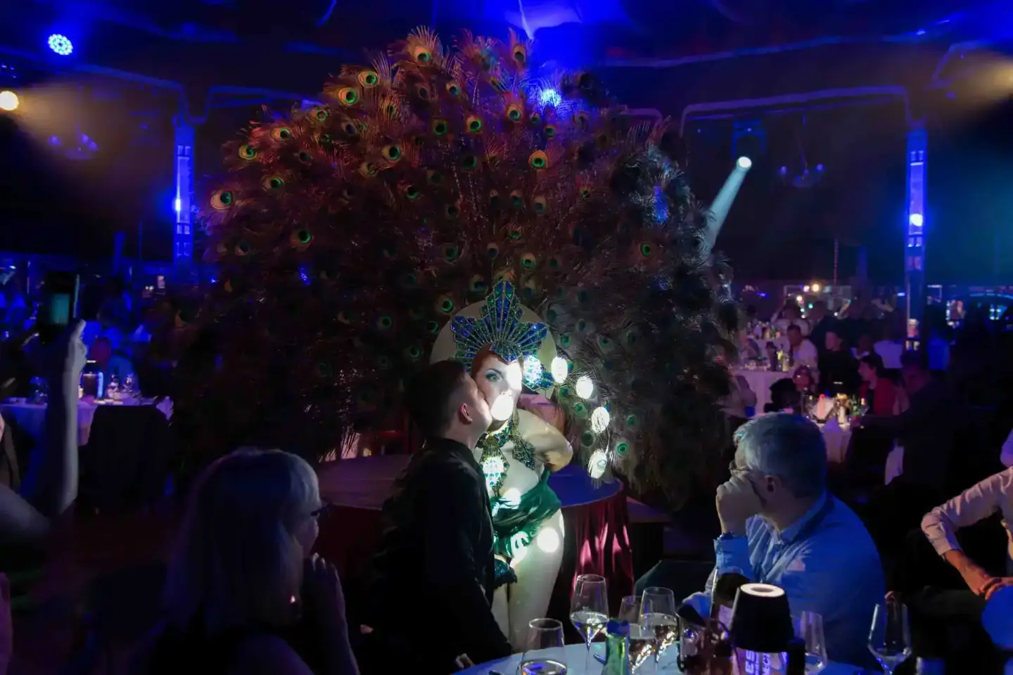 Elegante Gala-Veranstaltung mit Performerin in grünem Kostüm vor riesigem Pfau-Kunstwerk, Eventfotografie Wien