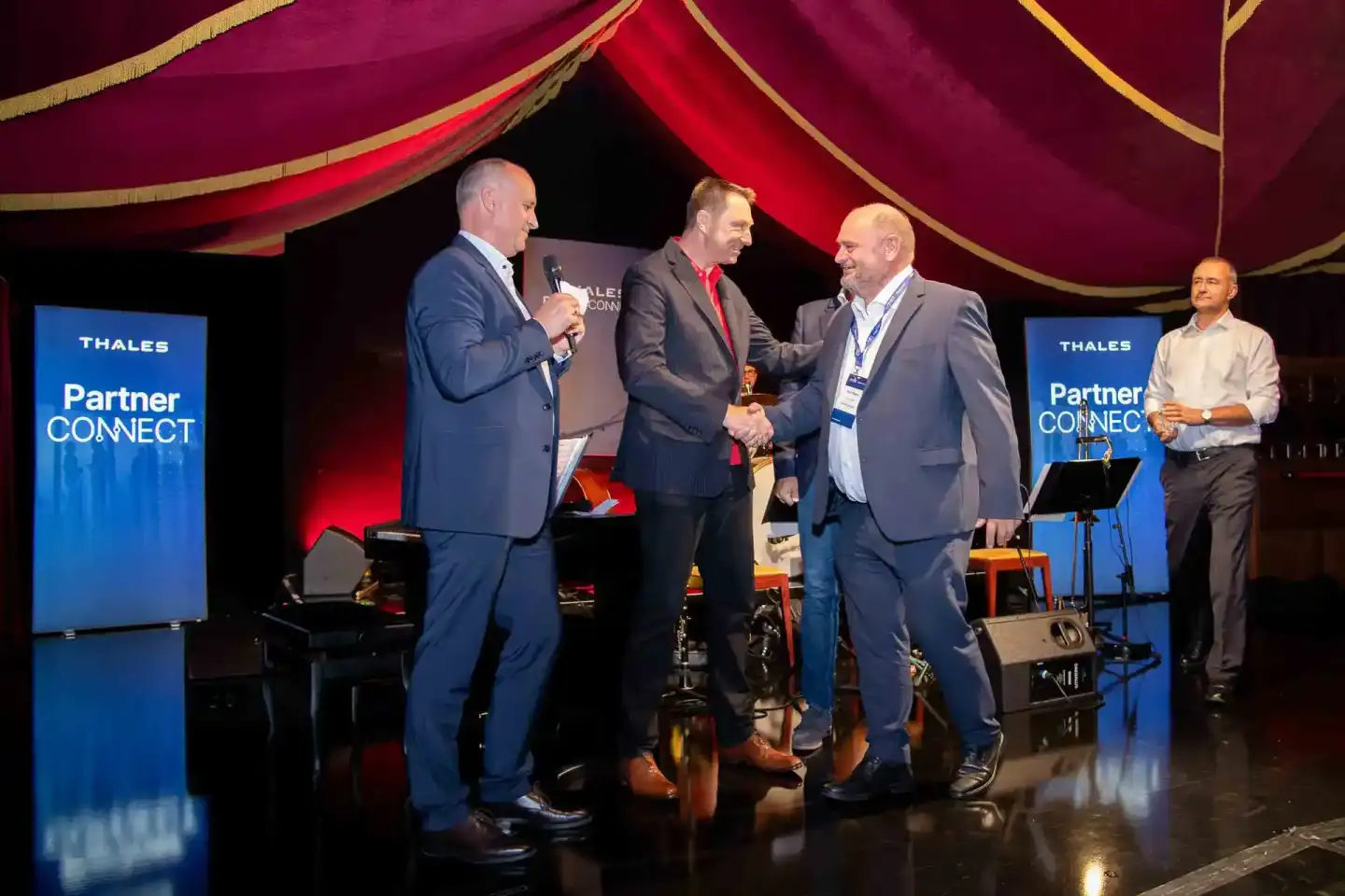 Vier Geschäftsmänner auf der Bühne der Thales Partner Connect Konferenz, Eventfotograf Wien dokumentiert die Veranstaltung