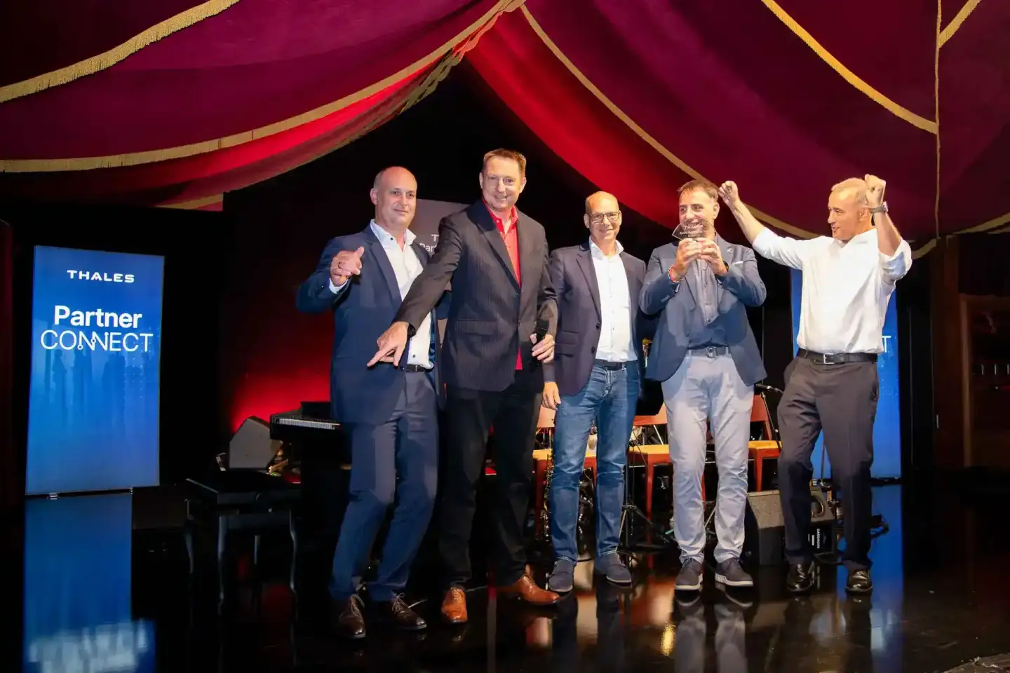 Fünf Geschäftsmänner auf der Bühne der Thales Partner Connect Veranstaltung in Wien, ein Eventfotograf dokumentiert die Unter