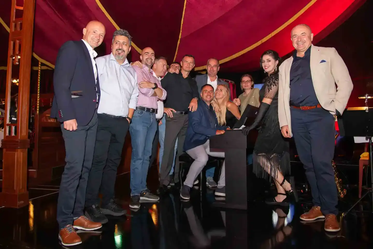 Gruppe von Gästen feiert beim Thales Firmenevent in Wien unter rotem Zeltdach, professionelle Eventfotografie Wien