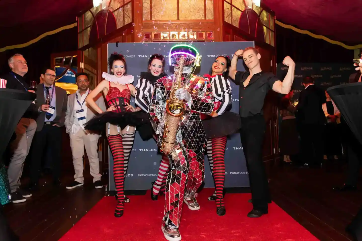 Eventfotograf dokumentiert glamouröse Thales Gala mit Tänzern in rot-weißen Kostümen und goldenem Pokal auf rotem Teppich