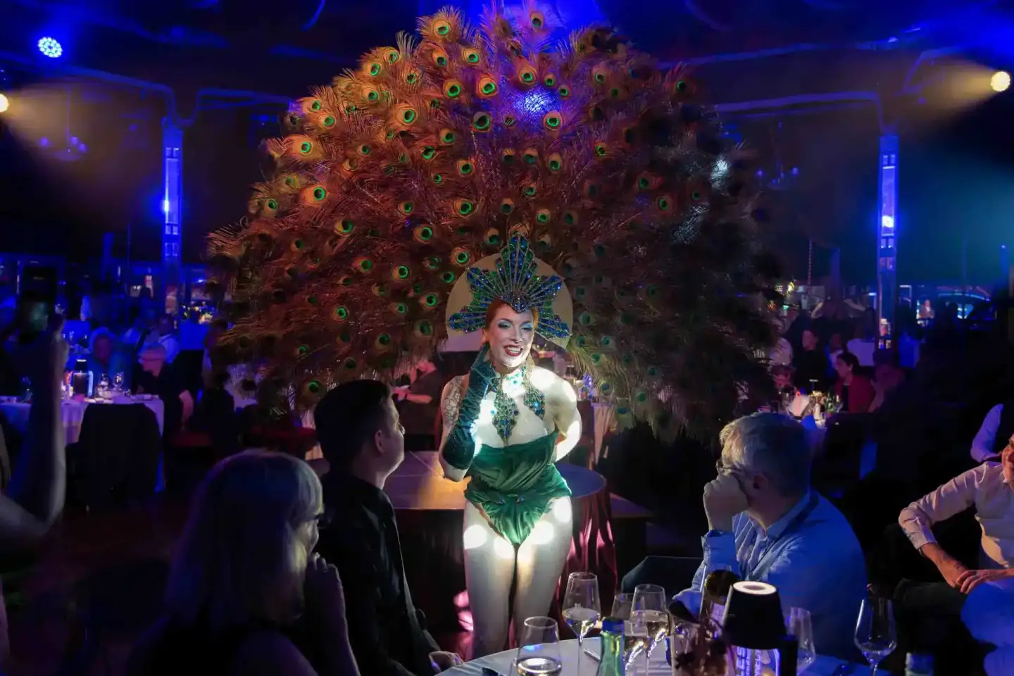 Performerin in grünem Kostüm mit großem Pfauenfeder-Kopfschmuck bei Gala-Event, Eventfotografie Wien