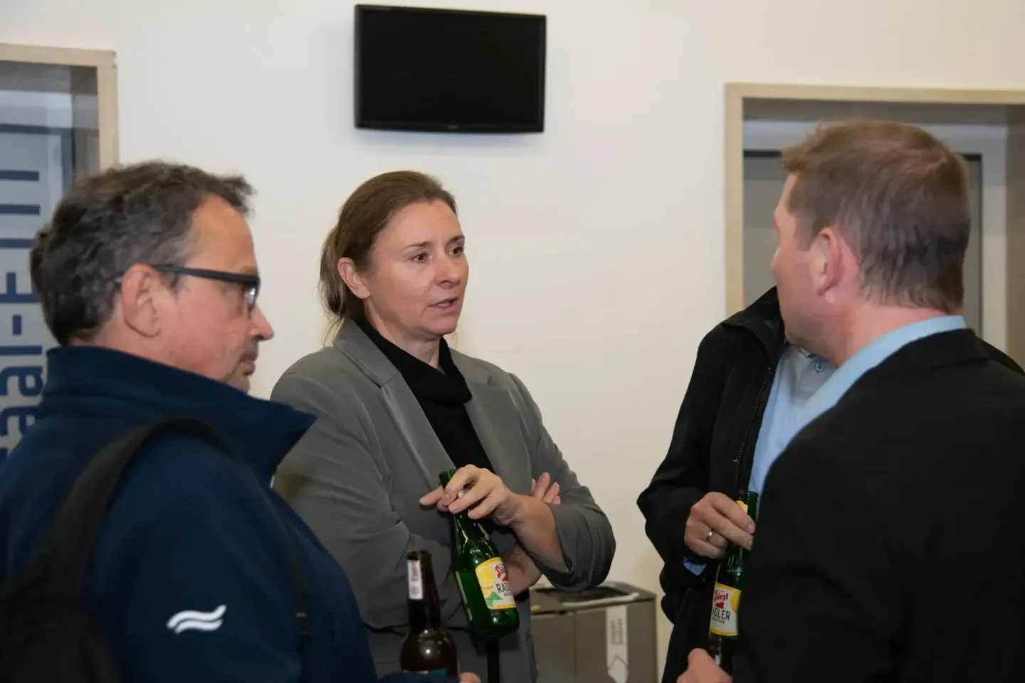 Drei Personen in Diskussion bei einem Firmenevent Wien mit Getränken in einem modernen Besprechungsraum