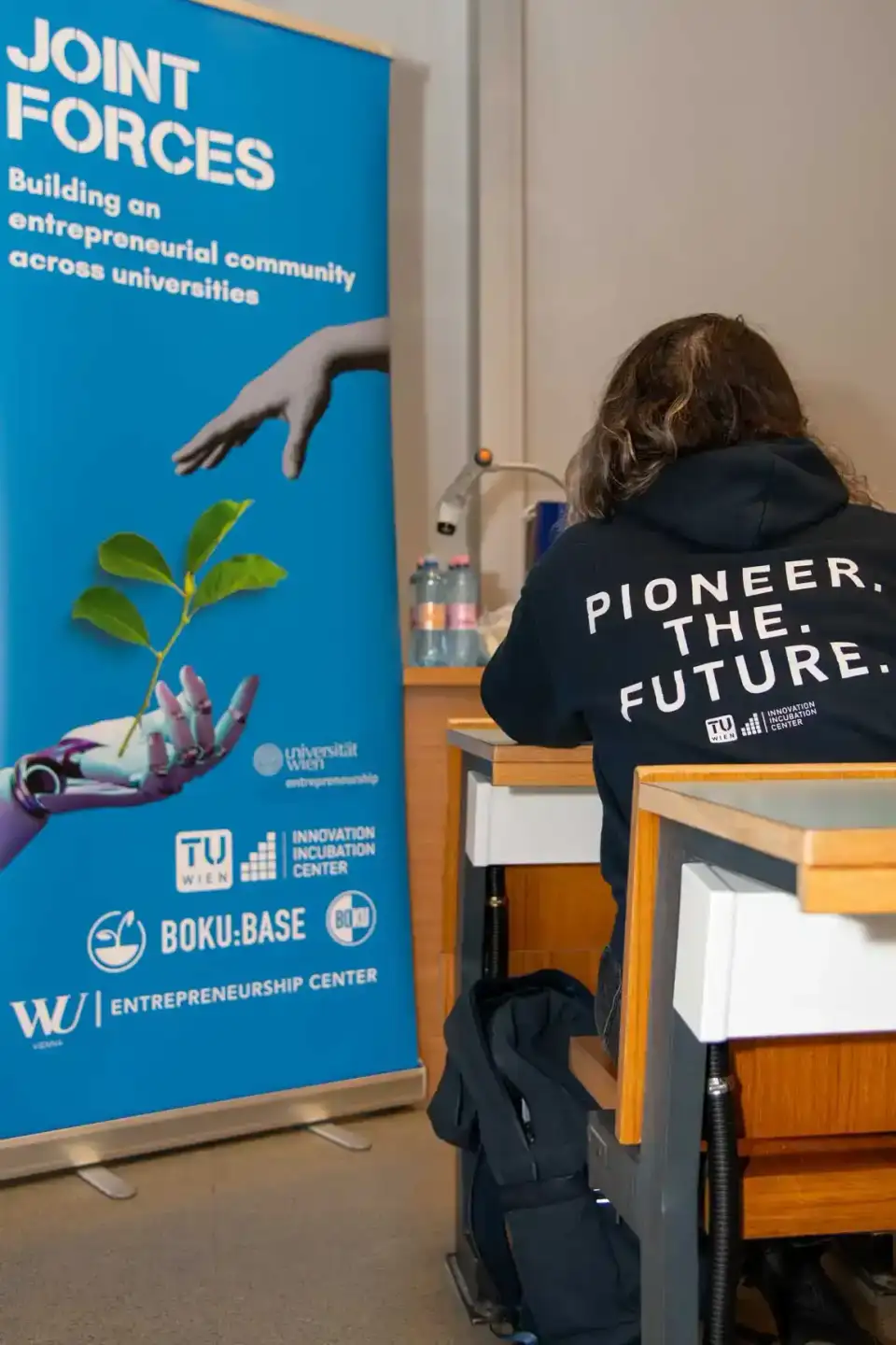 Teilnehmerin bei der Joint Forces Veranstaltung der TU Wien liest Informationen auf dem Plakat eines Eventfotografen Wien