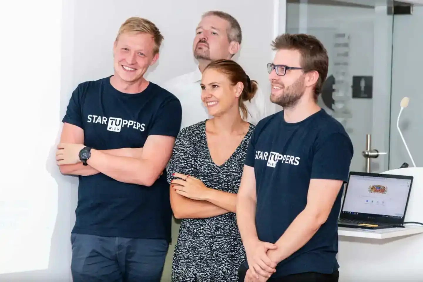 Team von vier Personen bei einem Firmenevent in Wien, drei tragen STARTUPPERS-Shirts, lächeln in die Kamera