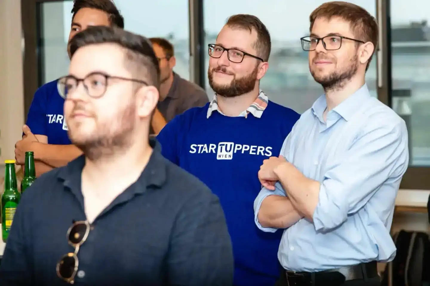 Gruppe von Männern beim Firmenevent in Wien, einer trägt ein Startupper-Shirt, lockere Atmosphäre mit Getränken