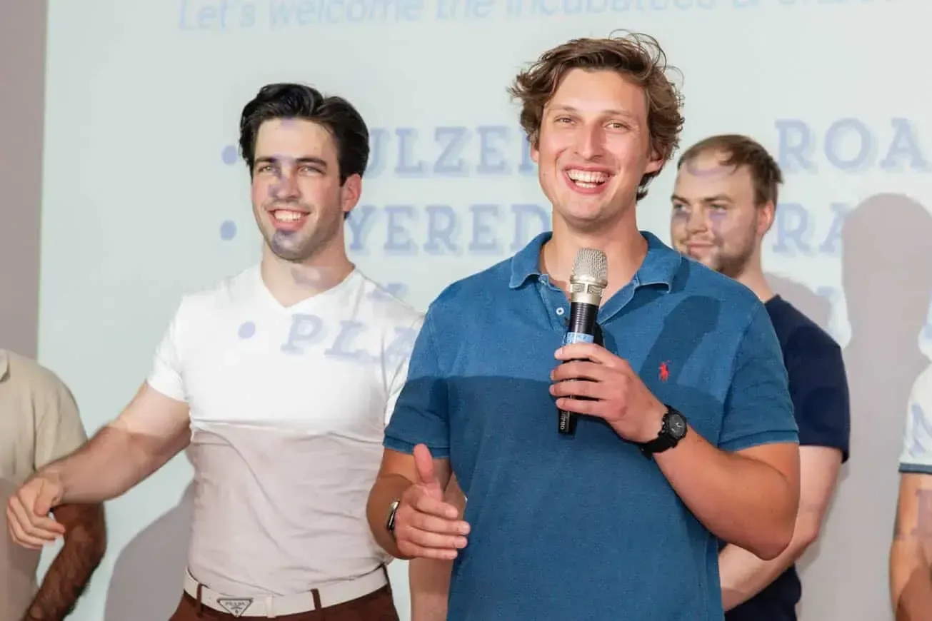 Drei junge Männer auf einer Veranstaltung in Wien, einer spricht mit Mikrofon vor Publikum - Eventfotografie