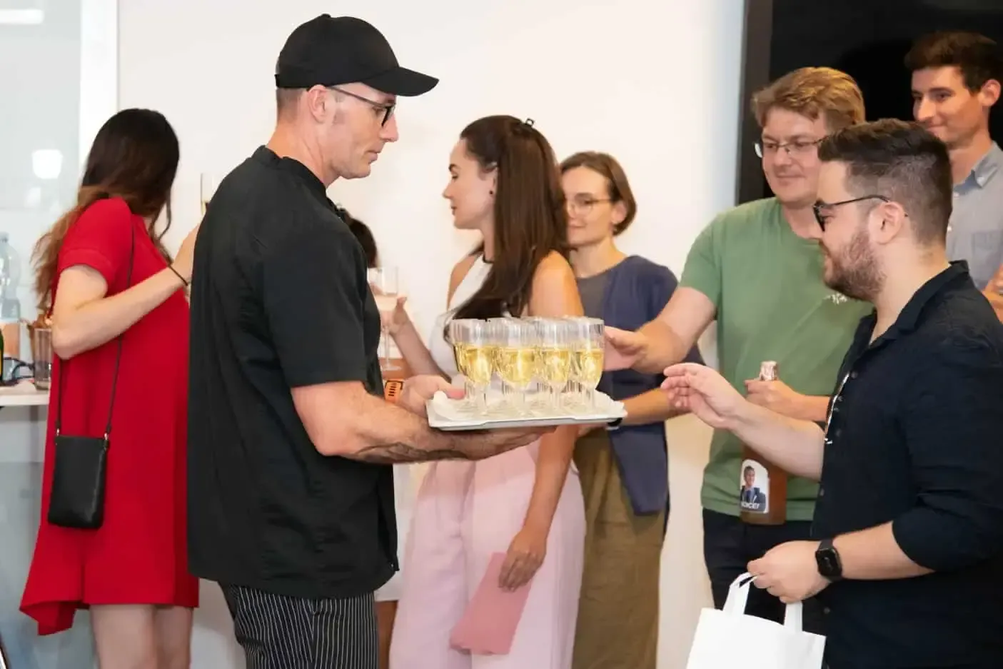 Eventfotograf dokumentiert Firmenevent in Wien: Mann in schwarzem Shirt serviert Champagner an Gäste