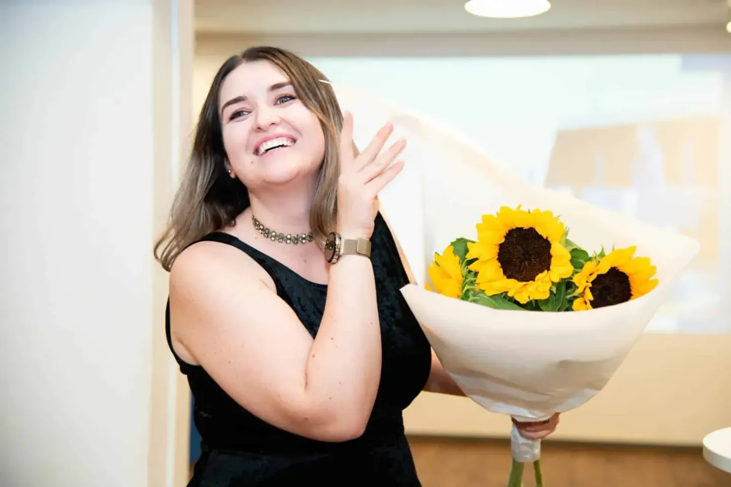 Frau mit Sonnenblumen bei Firmenevent Wien - Eventfotografie im modernen Veranstaltungsraum