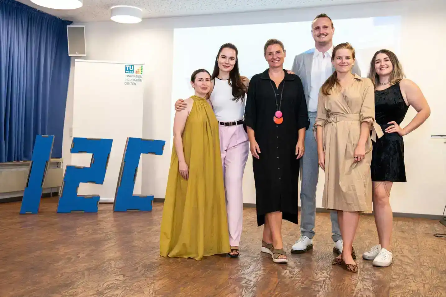 Team von sechs Personen beim Firmenevent Wien in der TU Innovation Incubation Center, posierend vor großem IET-Logo