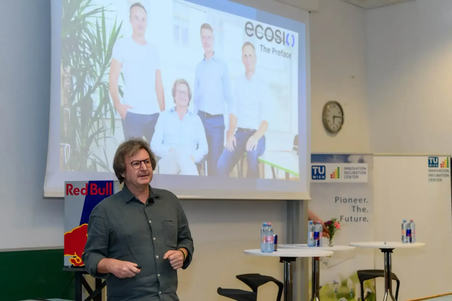 Eventfotograf präsentiert ecosio-Projekt vor Publikum auf TU Wien Veranstaltung mit Teamfoto und Red Bull Logo