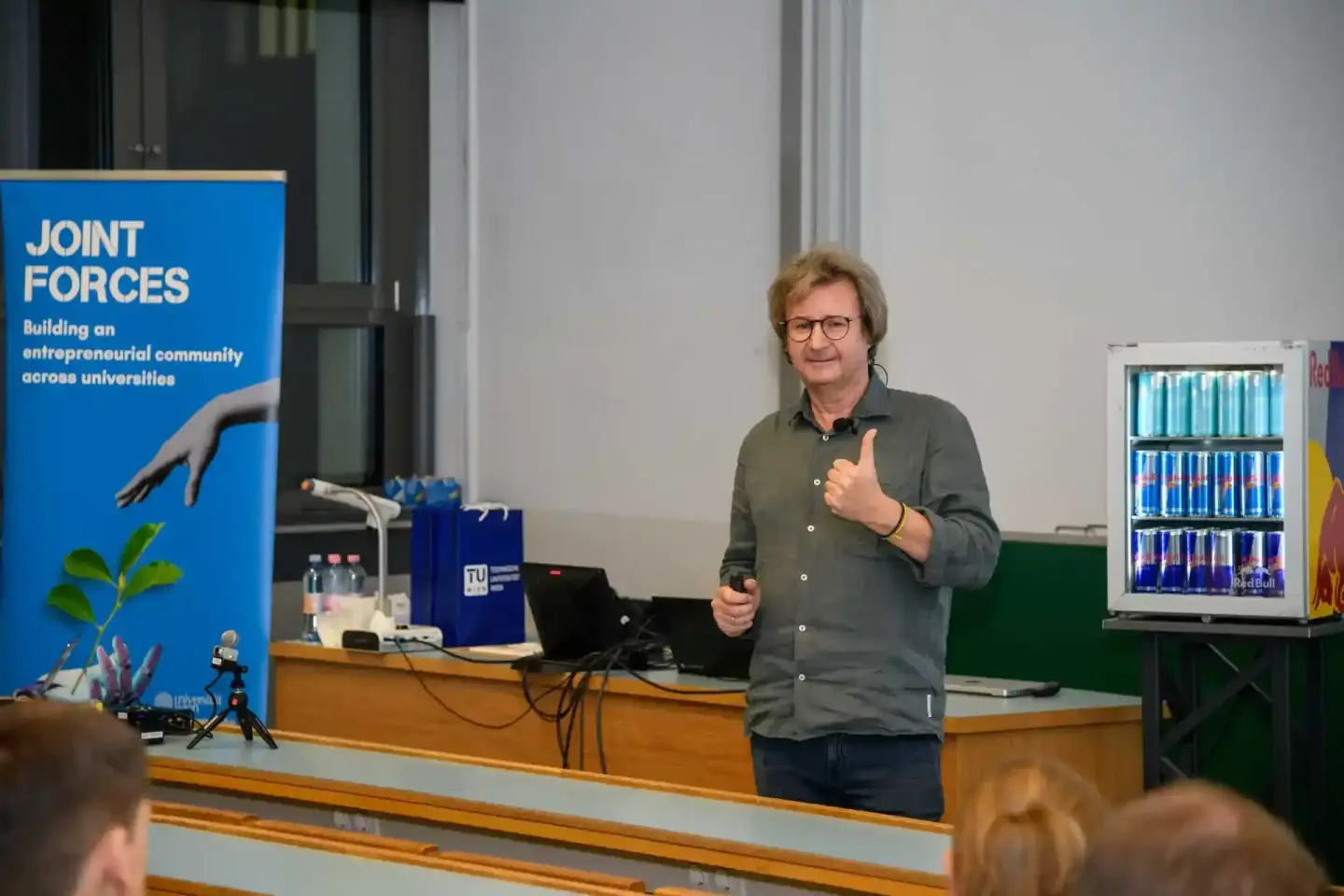 Eventfotograf dokumentiert Vortrag an der TU Wien mit Redner vor Joint Forces Banner