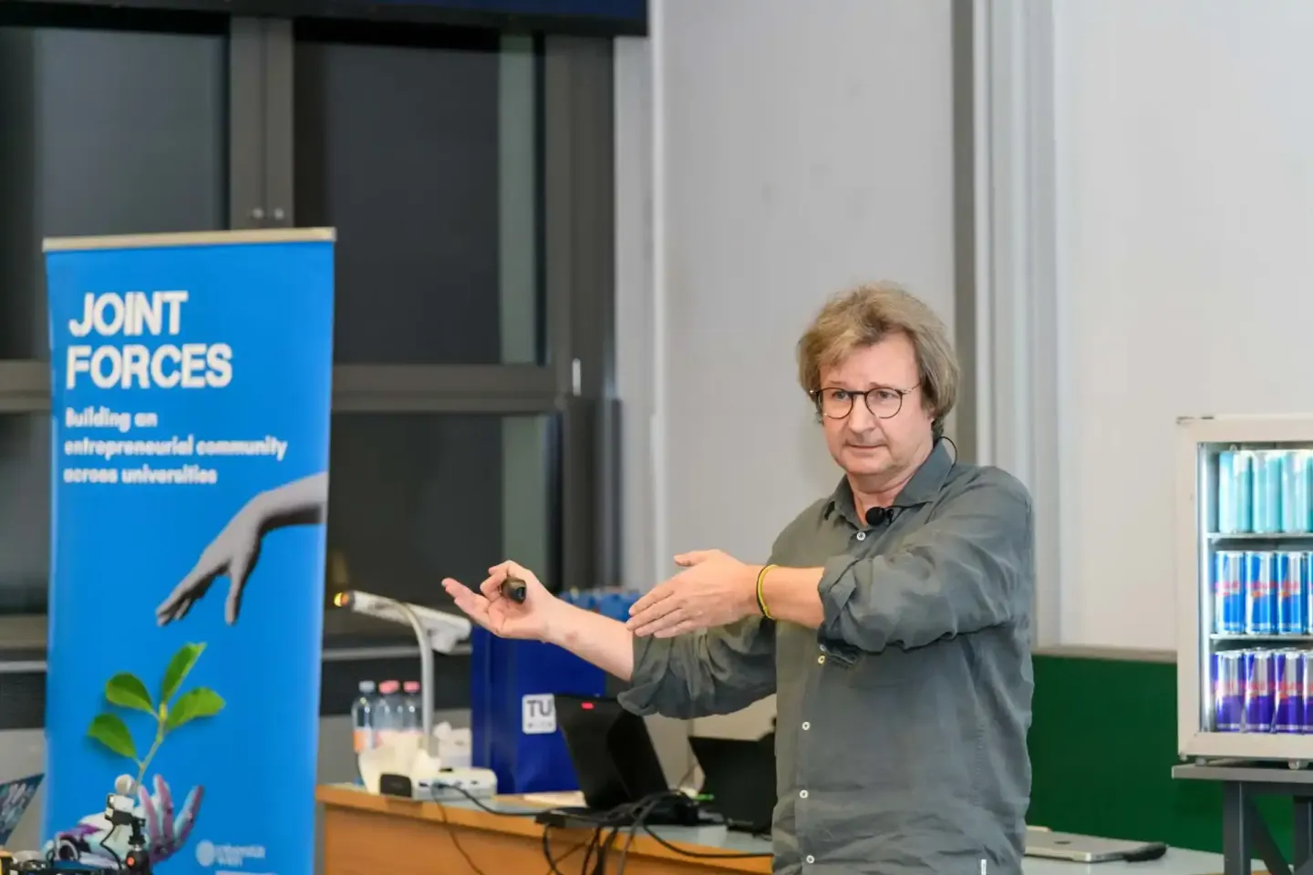 Vortragender bei TU Wien Event präsentiert vor blauem Joint Forces Banner, Eventfotograf Wien dokumentiert Vortrag