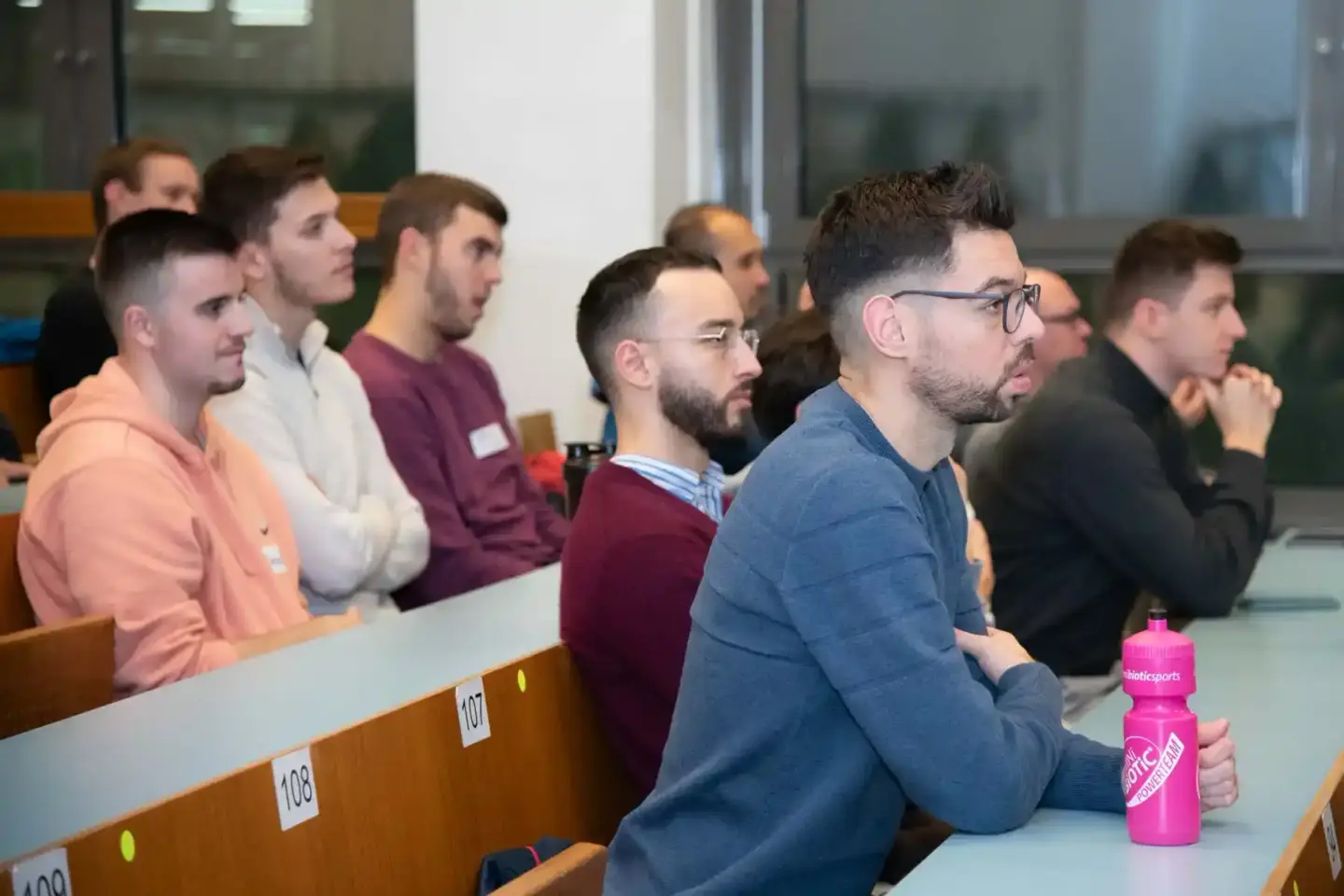 Gruppe von Männern sitzt in einem Hörsaal der TU Wien und verfolgt aufmerksam eine Veranstaltung, Eventfotografie Wien