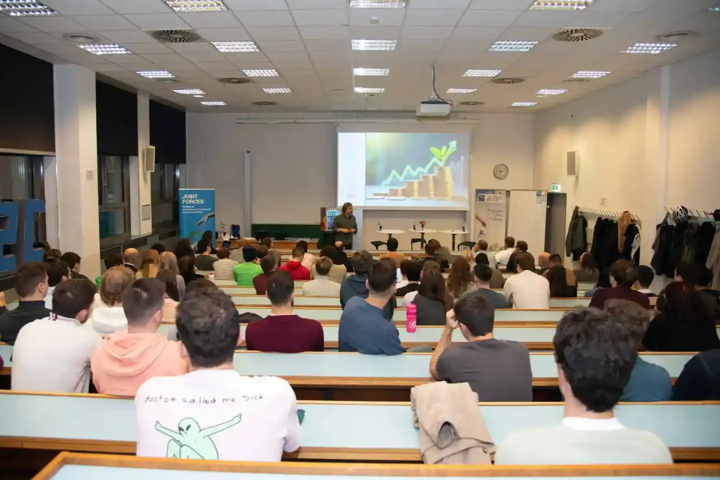 Eventfotograf dokumentiert Vorlesung an der TU Wien mit Hunderten Studierenden im Hörsaal, Projektionsfläche zeigt Wachstumsg